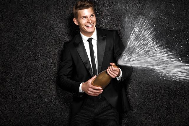 シャンパンを空けるスーツの男性